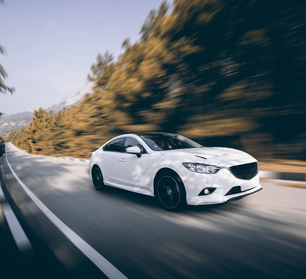 Berline blanche en vitesse sur une route de montagne Berline blanche dynamique roulant sur une route de montagne sinueuse avec effet de flou de mouvement.