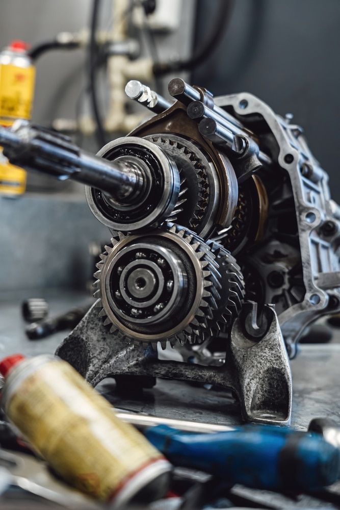 Réparation de Boîte de Vitesses : Zoom sur les Engrenages Boîte de vitesses automobile ouverte avec engrenages et roulements métalliques dans un atelier de mécanique.